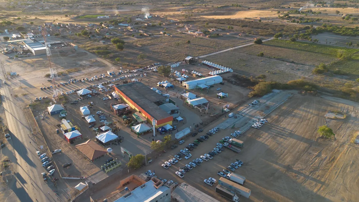Área de dinâmica de campo com máquina, tendas e público, vista do alto