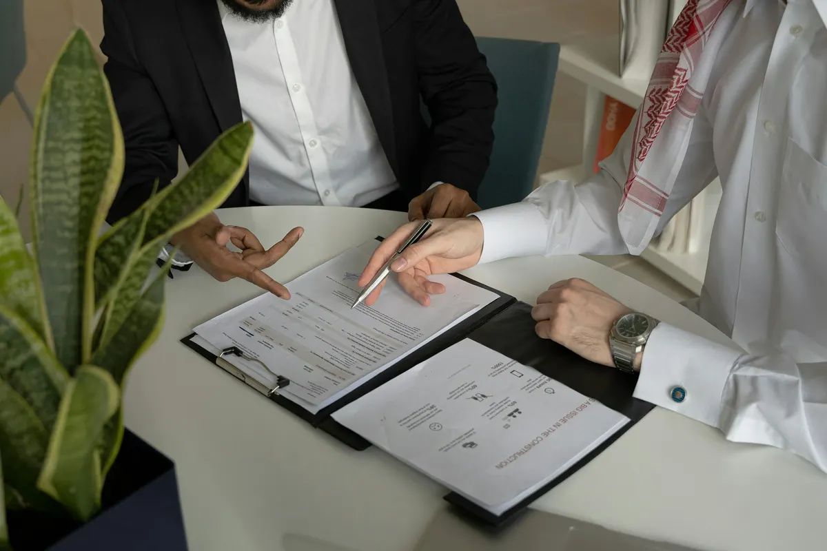 Duas pessoas assinando um contrato sobre a mesa